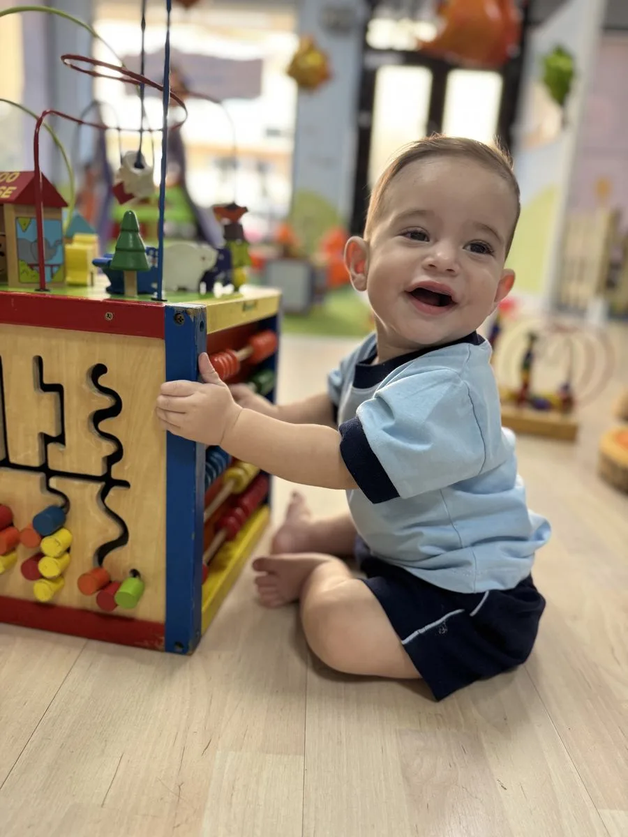 Bebé sonriendo mientras juega con un cubo de actividades