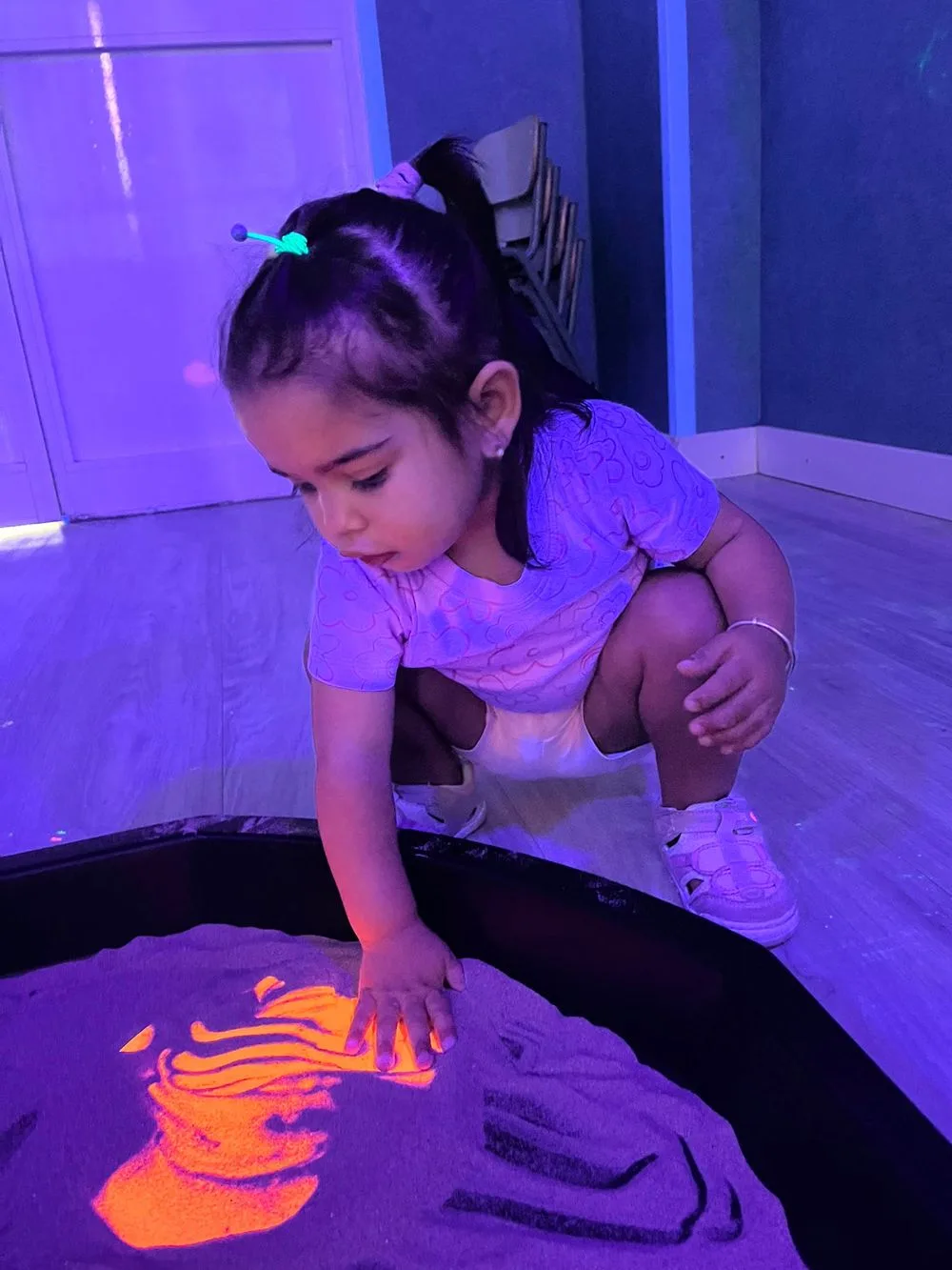 Niña experimentando con arena de colores en un taller sensorial